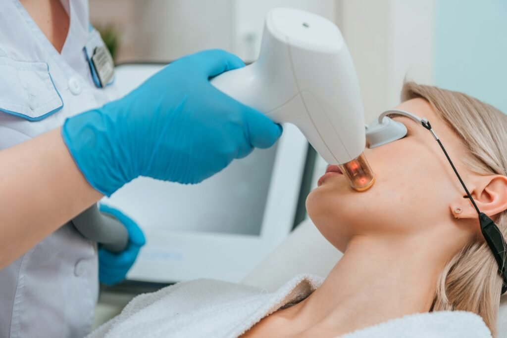 Blonde girl in protective goggles receiving laser treatment in clinic