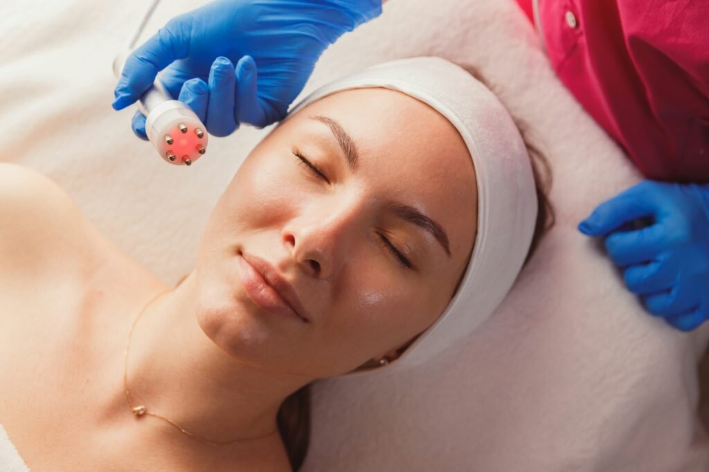 Facial Beauty Treatment. Woman Doing Red Led Light Therapy