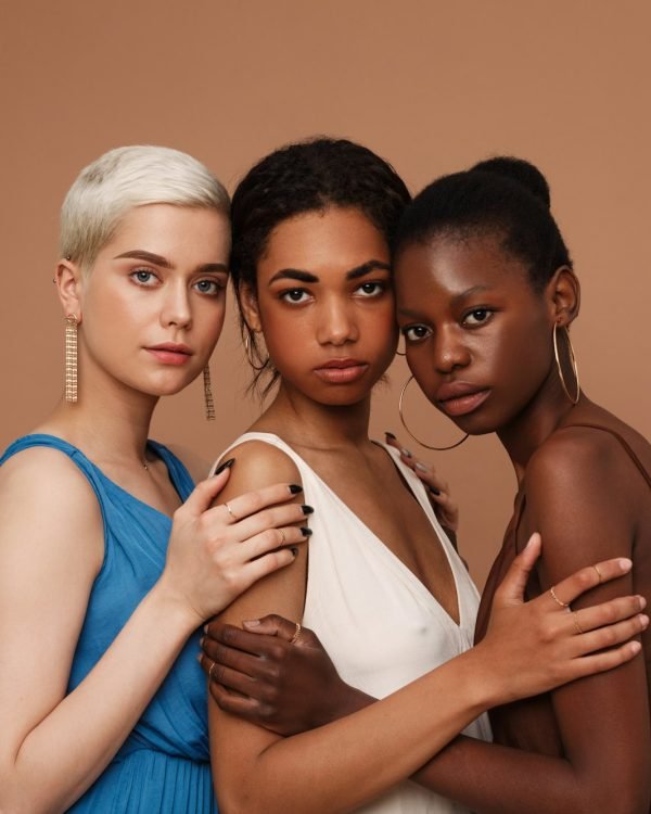 Three diverse women looking at camera. Young females with different skin tones standing together.